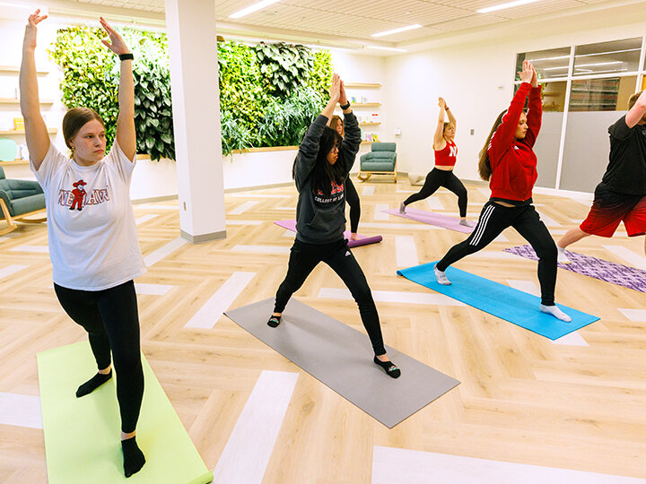 five students in the Wellness Room participating in a yoga pose