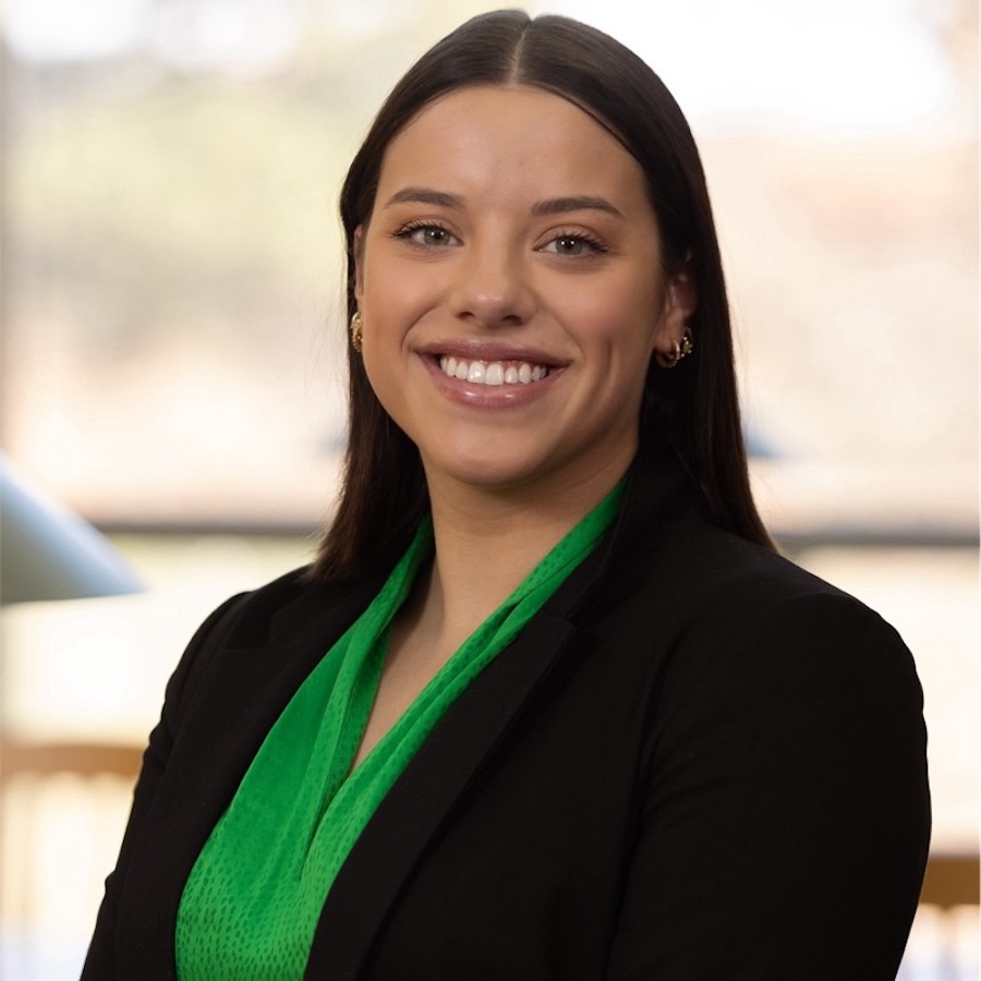 Headshot of Brenna, who is wearing a green shirt and dark blazer 