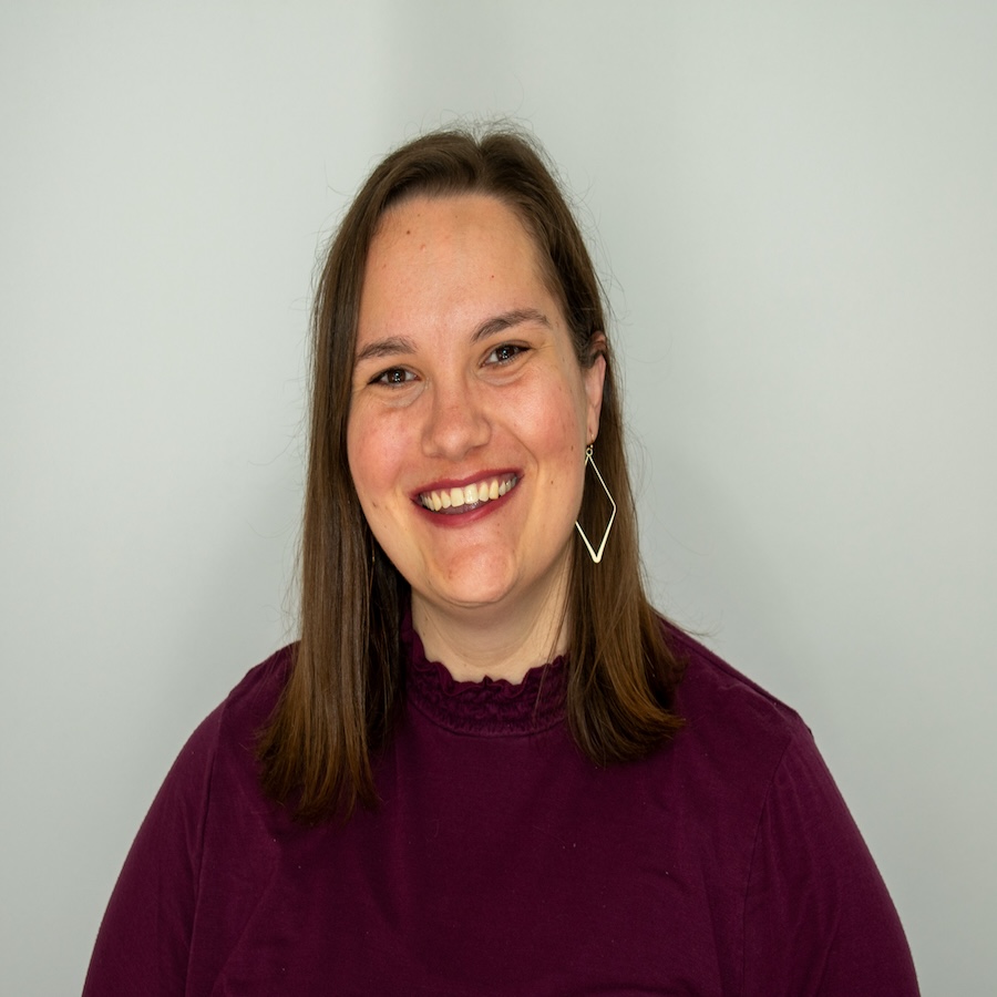 Headshot of Alison, who is wearing a dark red top and gold earrings 