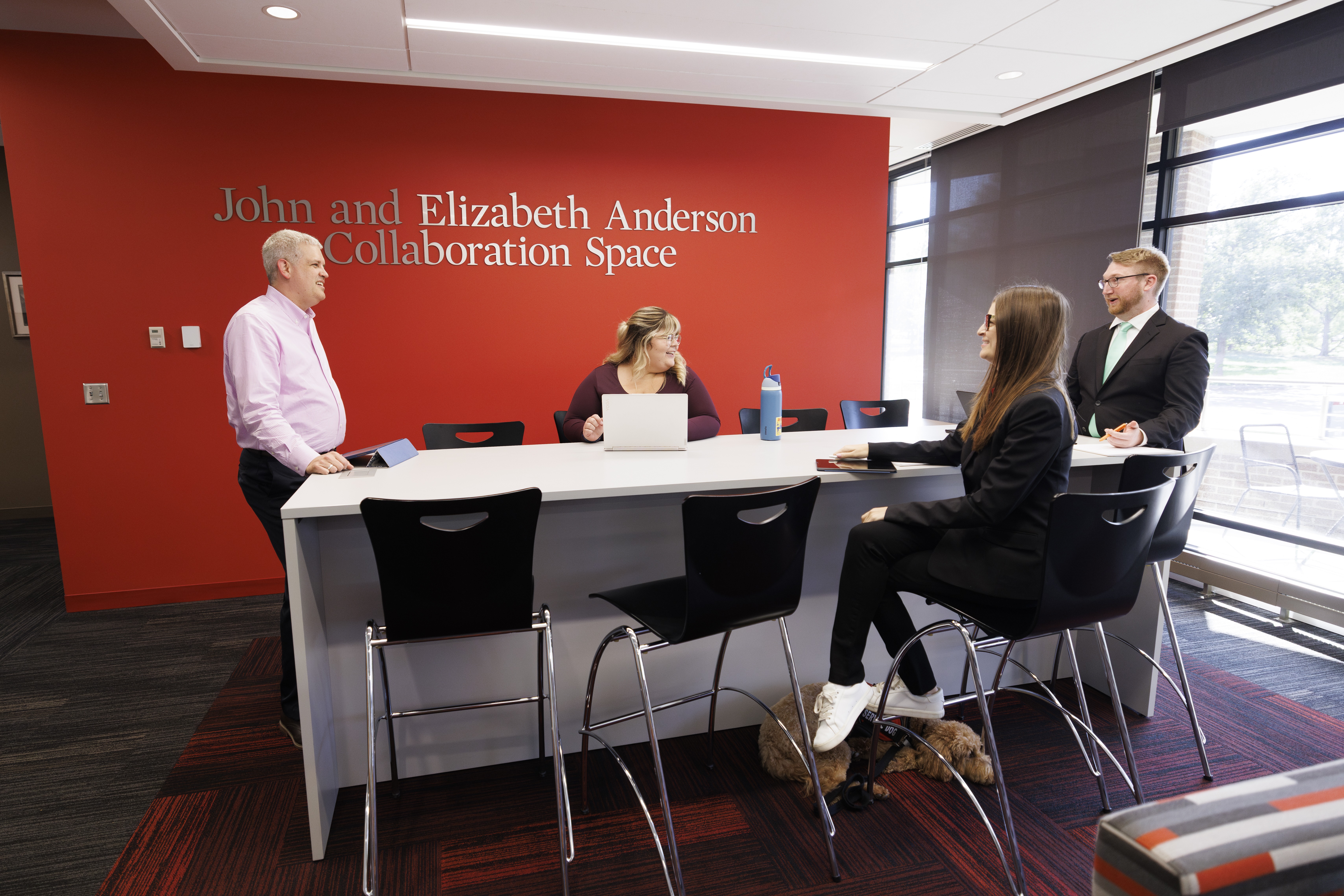 People engaged in discussion at a modern collaboration space with a red accent wall.