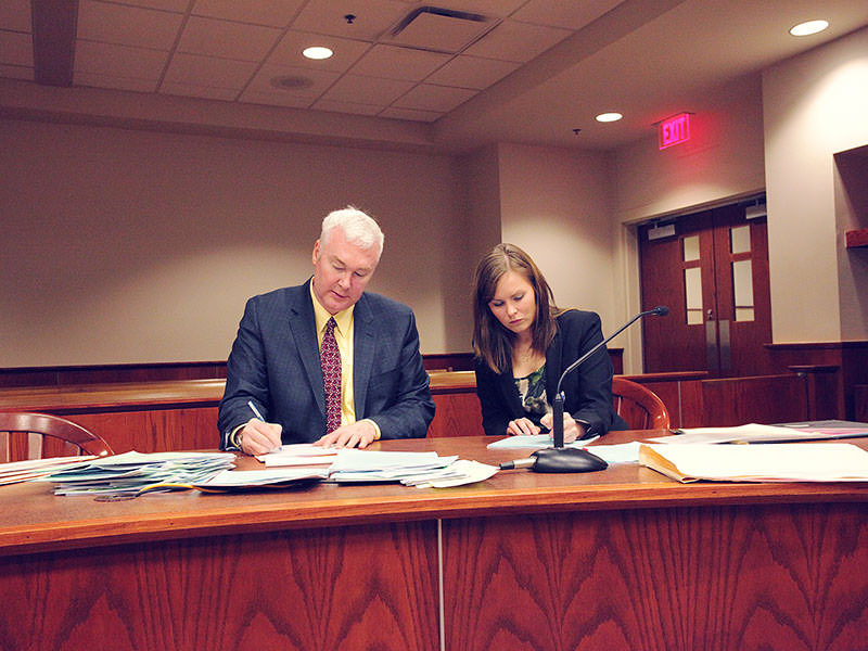 Two people writing at court desk