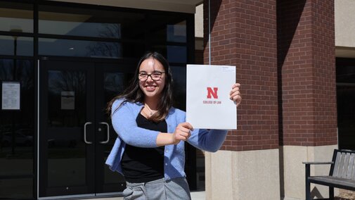 Student holding up folder with Nebraska College of Law logo on it