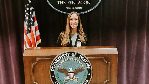 Student smiling and standing behind podium