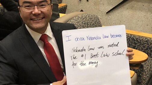 Student holding up whiteboard sign that says " I chose Nebraska Law because Nebraska Law was rated the #1 Best Law School for the money." 