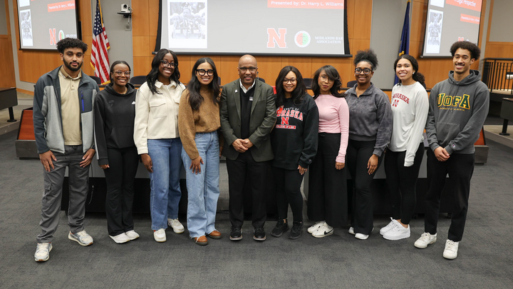 A group of students poses with a guest speaker in the auditorium