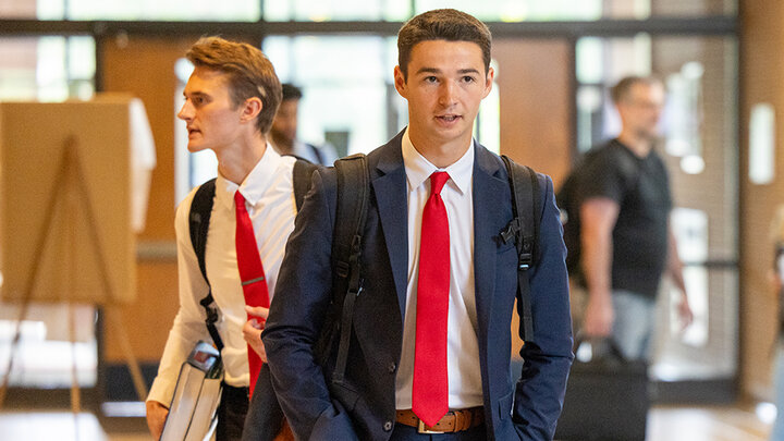 Student walking in the lobby in a suit and tie