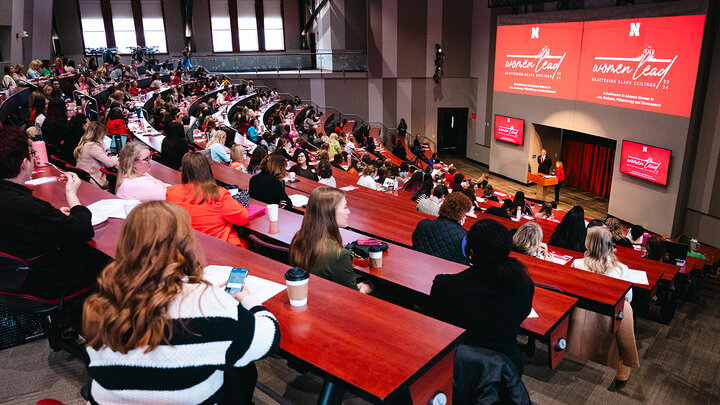 An auditorium full of people looking at two speakers in the front of the room