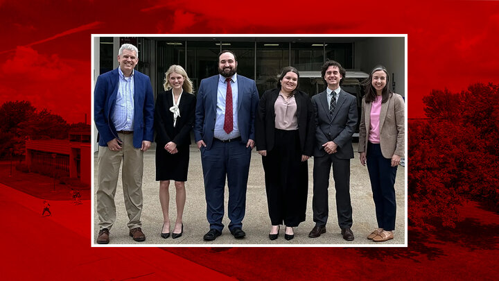 six people standing in front of law school building in professional attire