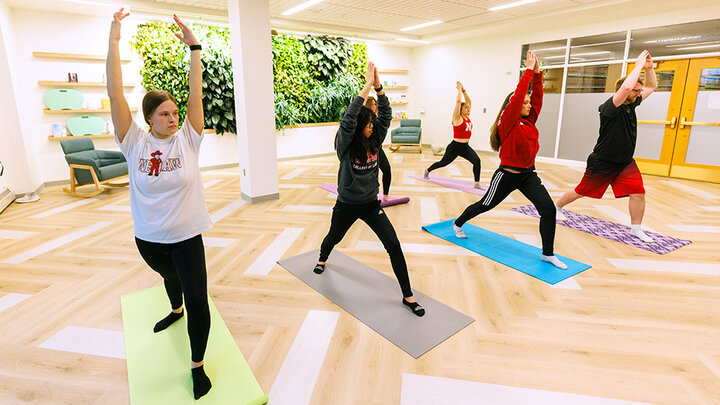 five students in the Wellness Room participating in a yoga pose