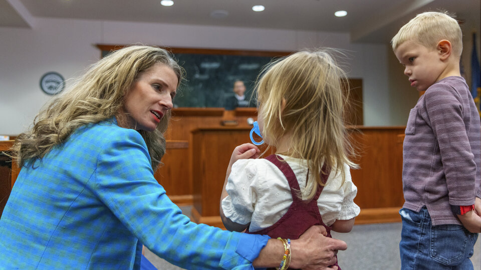 Michelle Paxton holding little girl and a boy stands next to her in a court room