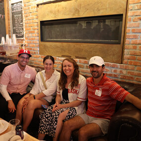 four people sitting on a sofa wearing Husker apparel and posing for a photo