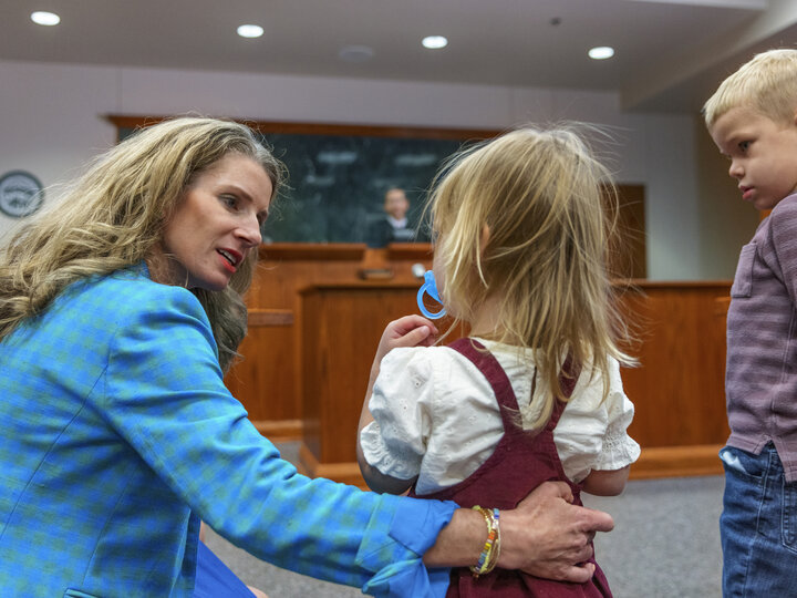 Michelle Paxton holding little girl and a boy stands next to her in a court room