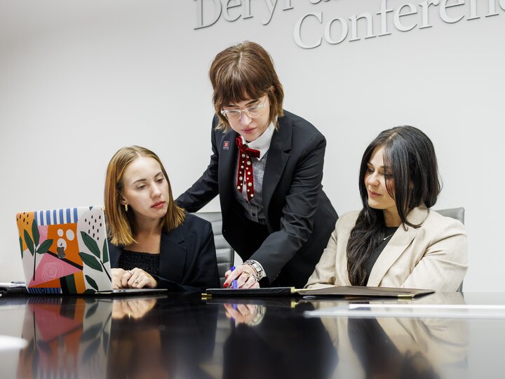 A professor reviewing a document with two students at a conference table
