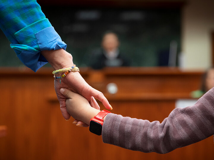Child holding lawyer's hand with judge in the background