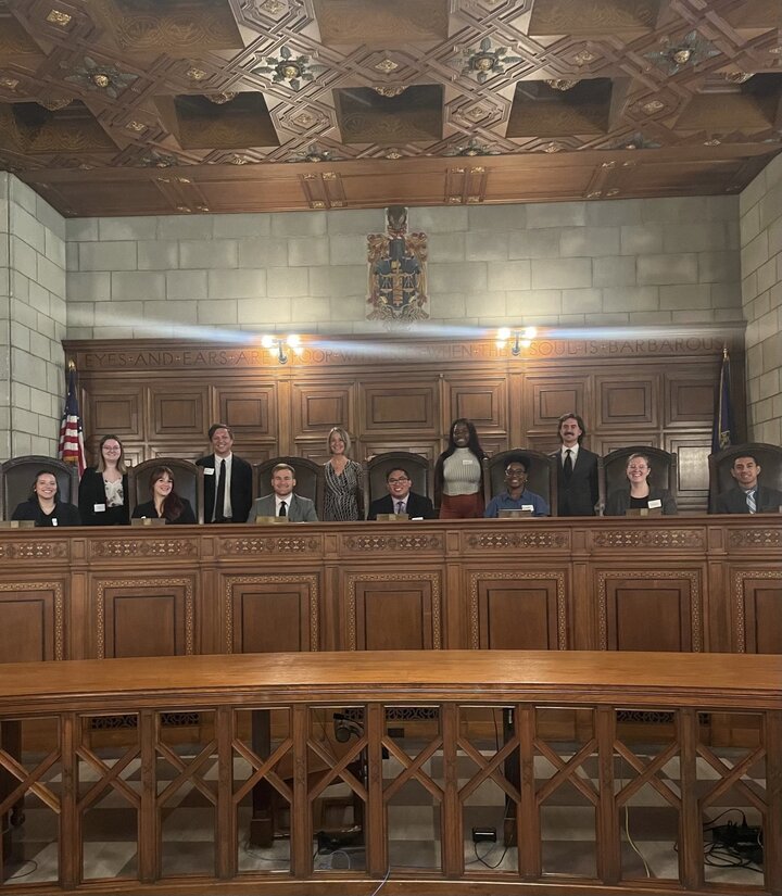 Several law clerks from Legal Aid of Nebraska are pictured with Nebraska Supreme Court Justice Stehanie Stacy either seated or standing on the bench of the Nebraska Supreme Court. 