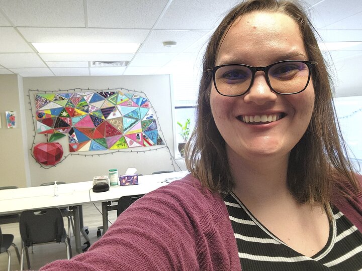 Selfie of Alison in the Nebraska Appleseed office with Nebraska art in the background