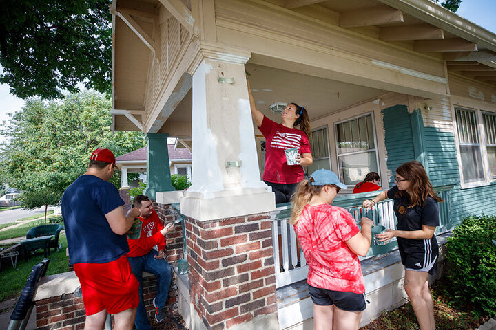 People painting the front porch of a house