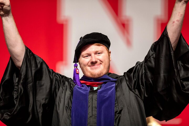 Graduate raising arms and smiling